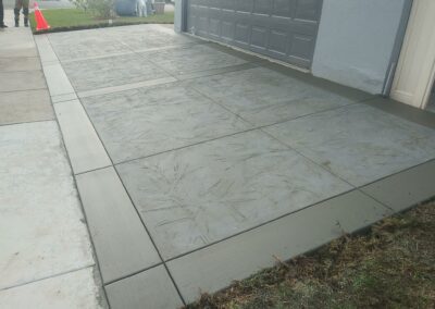 A driveway with a concrete walkway in front of a house.