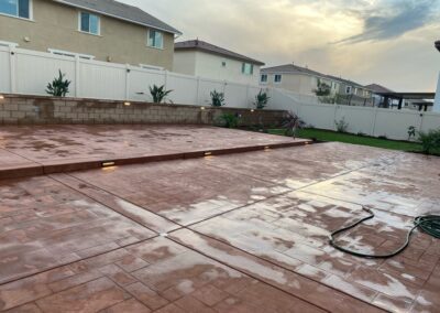 A backyard with a concrete patio and a hose.