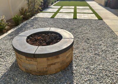 A fire pit in a backyard with gravel.