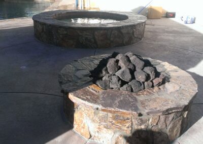 A fire pit sitting on a patio next to a pool.